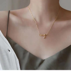 Elegant gold bamboo joint pendant necklace with leaf charm worn by a female model