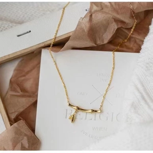 Detail of gold bamboo node necklace featuring a small sprout pendant on white card