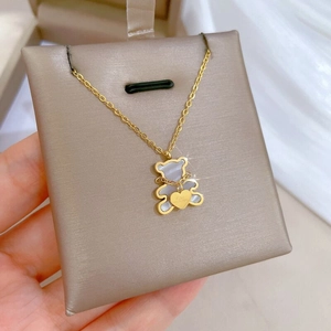 Close-up of golden bear necklace with white mother-of-pearl inlay and tiny heart charm