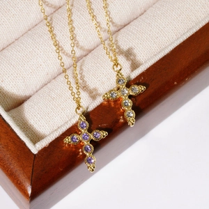 Cross pendant necklaces with colorful crystals in gold-plated finish on a velvet display