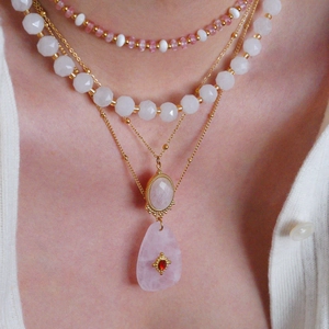 Layered gold necklace featuring pink natural stones and crystal beads on a female model
