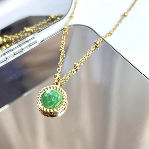 Detail of 14K gold plated necklace with green faceted stone and twisted pendant border