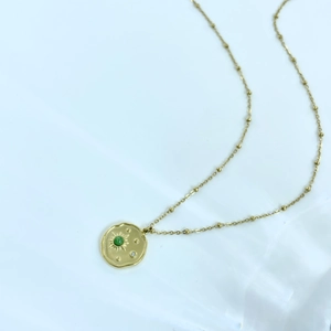 Detail shot of a 14K gold-plated sunburst pendant with a green malachite stone and bead chain