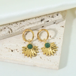 Golden hoop earrings with green sunburst charm displayed on elegant beige travertine stone