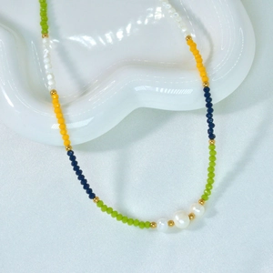Bunte Perlenkette mit natürlichen Perlen und Goldakzenten auf Keramikschale