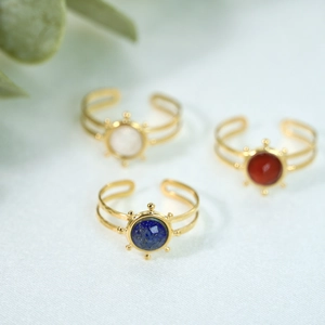 Detail of adjustable golden rings featuring vibrant round gemstones in sunburst settings