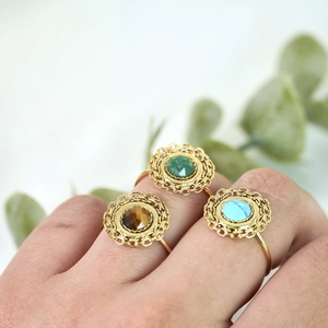 Close-up of bohemian gold rings with hollow lace edges and colorful faceted natural stones