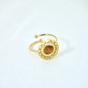 Close-up of bohemian gold open ring featuring a brown gemstone and woven metal edge