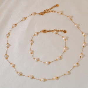 Detail of natural pearl necklace and bracelet set with S.steel tag on silk background