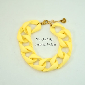 Detail eines gelben Acryl-Gliederarmbands mit goldenem Karabiner und Herz-Anhänger