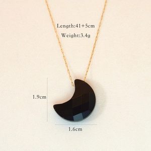Macro detail of moon-shaped black stone pendant on gold stainless steel chain