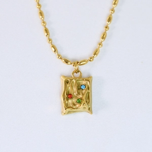Detalle del collar chapado en oro de 14k con circonitas de colores y diseño martillado
