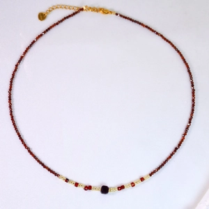 Détail du collier de perles rouges avec perle carrée pourpre et fermoir doré