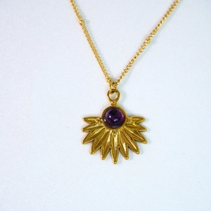 Dettaglio macro del ciondolo bohémien a girasole con pietra viola su catena oro