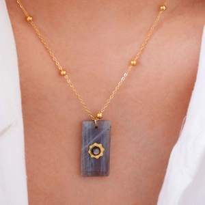 Detail view of square natural stone pendant necklace with gold sun flower inlay