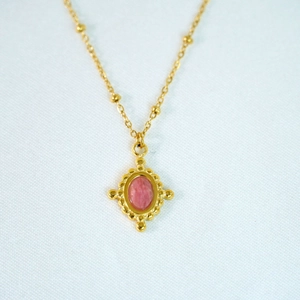 Detailed view of vintage gold necklace featuring a pink oval gemstone and bead chain