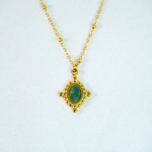 Macro view of 14k gold beaded necklace with vintage green gemstone pendant