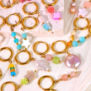 Detalle de aros dorados con piedras naturales, perlas barrocas y colgantes de conchas