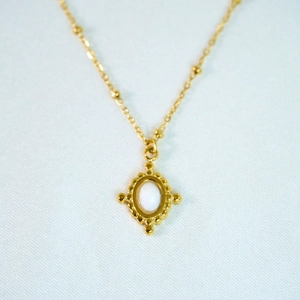 Close-up of vintage 14k gold satellite chain necklace with milky white opal pendant