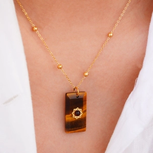 Detail of square natural stone pendant with gold sun flower charm on beaded chain