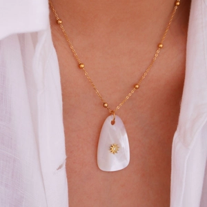 14K gold plated necklace with teardrop shell pendant and starburst detail on model