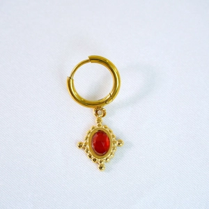 Detail of vintage gold-plated earrings with oval red gemstone and baroque textured bezel
