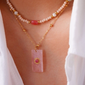 Dettaglio di collana a doppio strato con ciondolo in pietra rosa e fili di perle colorate