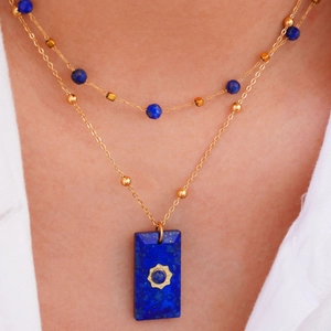 Dettaglio di una collana a due strati in oro 14K con perle blu e ciondolo a stella