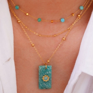 Macro shot of tiered bohemian necklace with natural square stone pendant and gold chains