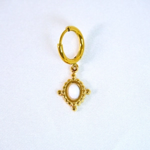 Macro detail of gold hoop earring featuring a white oval stone in a vintage frame