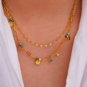 Double-layered gold stainless steel necklace featuring green beads and round charms on a model
