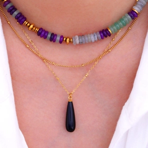 Detail einer Boho-Schichtenkette mit bunten Perlen und schwarzem Tropfenstein-Anhänger