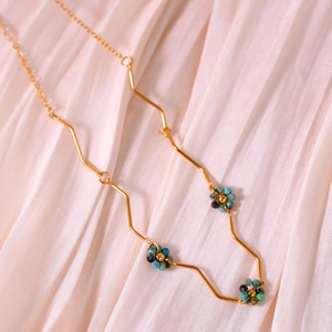 Detail of bohemian gold layered necklace with turquoise beads on pink pleated satin