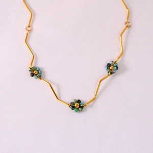 Detail of gold zigzag chain with blue and green beaded flower charms for women