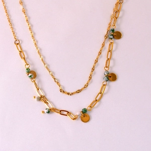 Detail of gold double-layer necklace with paperclip chain, marble beads and metal coins