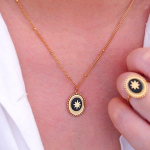 Close-up of gold starburst necklace and ring set with black oval stone inlay