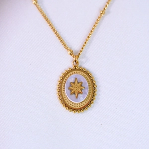 Detailed macro view of an oval mother of pearl star pendant on a gold bead chain