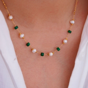 Close-up of gold beaded necklace with malachite and pearls worn on female model neck