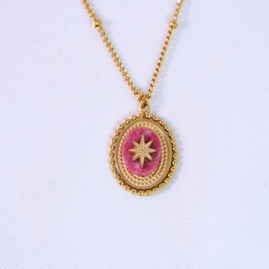 Detail of bohemian gold star pendant featuring an oval pink natural stone inlay