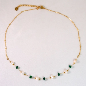 Detail view of gold chain necklace featuring white pearls and green square malachite beads