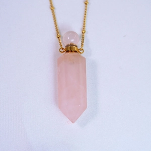 Detailed close-up of rose quartz perfume bottle pendant with gold cap and beaded chain
