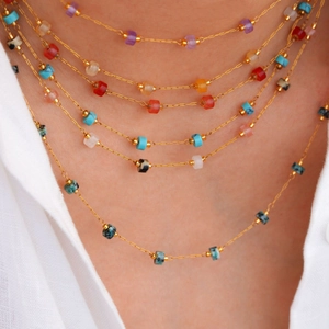Primer plano de collares de cadenas de oro con cuentas de piedras naturales en una modelo