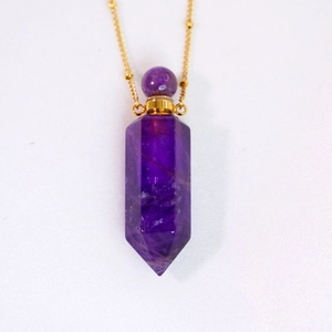 Macro shot of purple amethyst hexagonal perfume bottle pendant with golden metal chain