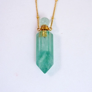 Close-up of light green hexagonal crystal perfume bottle pendant with a gold chain