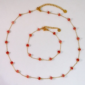 Vista detallada de conjunto de collar y pulsera de acero dorado con cuentas rojas