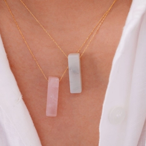 Primo piano dettagliato di collane a doppio strato in oro 14K con pendenti in pietre naturali rosa e bianche