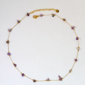 Detailed macro view of handmade gold chain necklace with purple stones and lobster clasp