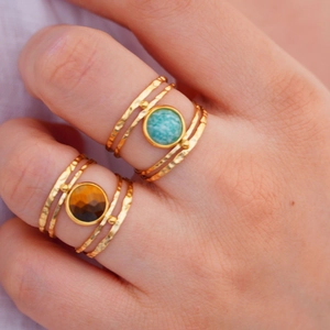 Close-up of 14k gold plated rings with natural green and brown stone inlays