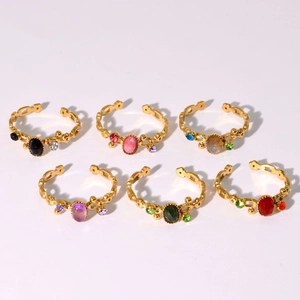 Detail of six gold-plated adjustable rings with colorful oval stones and wavy band