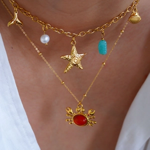 Close-up of layered gold ocean necklaces with crab, starfish, and pearl charms